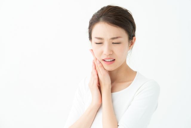 手で頬を押さえて痛そうにしている女性