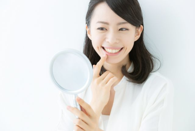 鏡で歯を見る女性